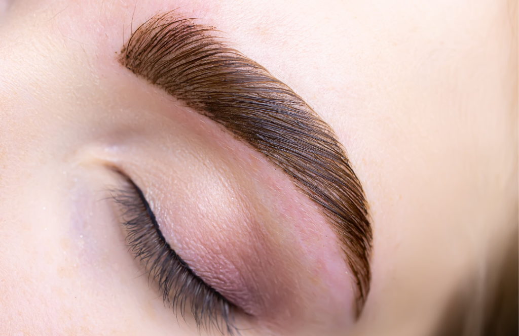 A close-up of a woman's eye featuring a striking brown eyebrow, highlighting the natural beauty and detail of her gaze.