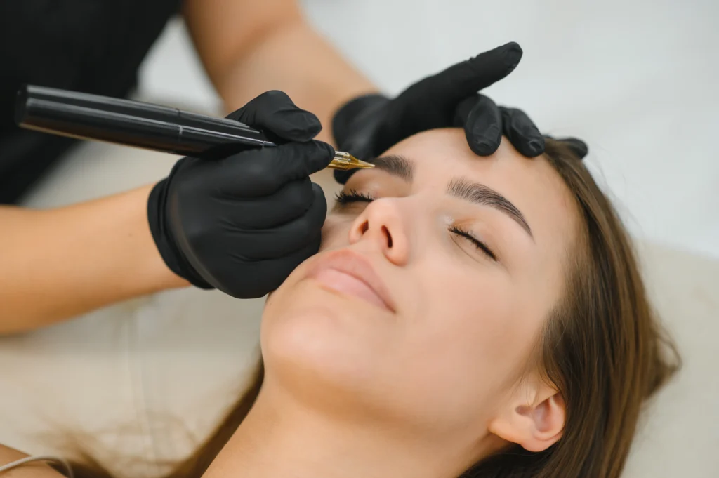 A cosmetologist applies permanent makeup to the eyebrows - eyebrow tattoo.