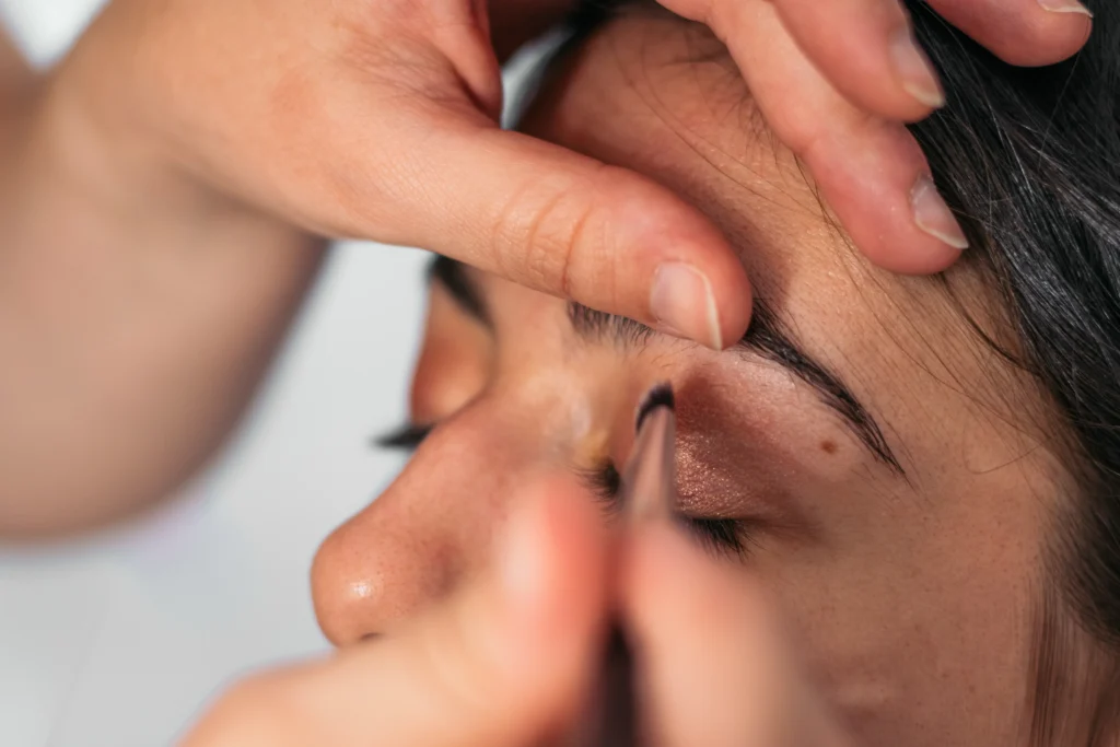 Close-up of a woman having her eyes done by a professional make-up artist in a lighted studio