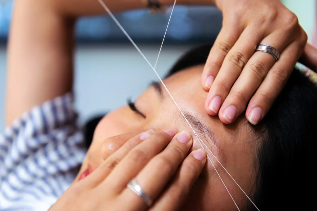 Eyebrow waxing with threading on a young woman