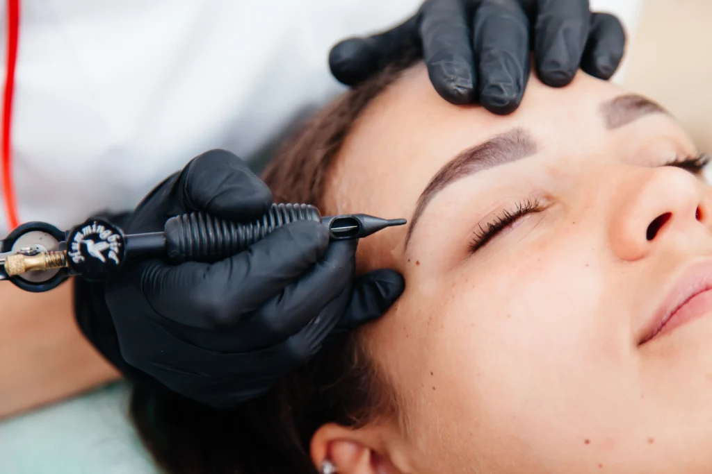 Permanent tattoo brow makeup, beauty studio master making beautiful brows on female face.